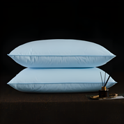 Two light blue pillows on a dark surface with a small decorative item.