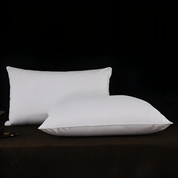 Two white pillows on a dark surface with a black background
