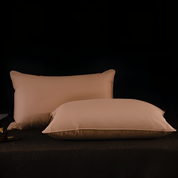 Two beige pillows on a dark surface with a black background