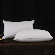 Two white pillows on a dark surface with a black background