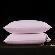 Two pink pillows on a dark surface with a small decorative item.